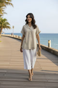 Woman in Linen Essentials Vneck top walking along a boardwalk by the beach, showcasing summer style in comfort.