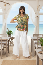 Model wearing Cecilia t shirt with colorful prints, relaxed fit, in a beachside setting with vibrant scenery.