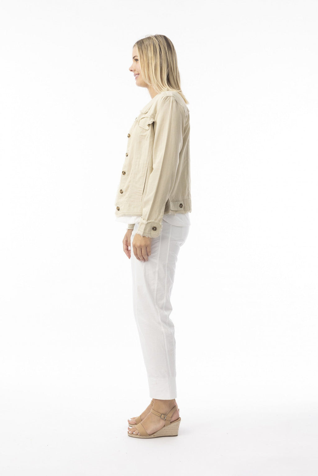 Side view of a woman wearing the Essentials Jacket sand with frayed trim and front bust pockets.