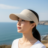 Woman wearing an Adjustable Sport sunviser by the ocean, stylish in a beige color, perfect for outdoor activities.