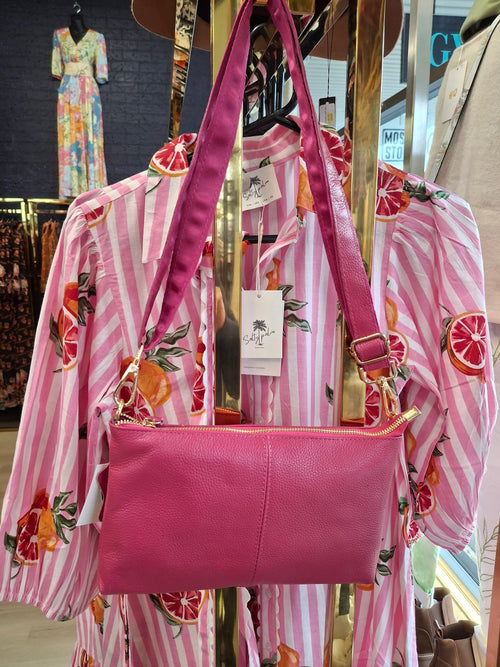 Atn Crossbody Leather Bag hanging on a display, featuring a vibrant pink color and stylish design.
