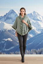 Model wearing a stylish Camilla Shawl with faux fur trim, set against a snowy mountain backdrop.