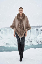 Model wearing the elegant Camilla Shawl with faux fur trim, set against a snowy backdrop near waterfalls.