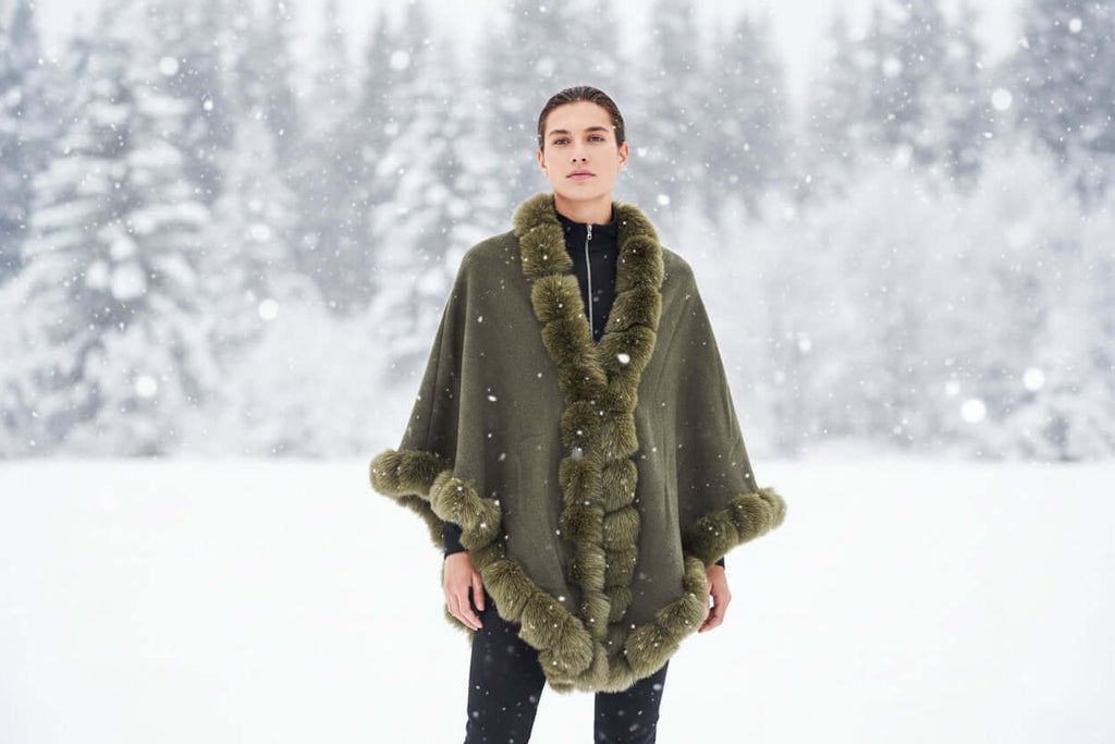 Model wearing the Camilla Shawl with luxurious faux fur trim in a snowy landscape.