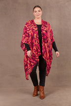 Mayan Cape in vibrant pink and orange design, lightweight with 3/4 sleeves and handkerchief hem, perfect for layering.