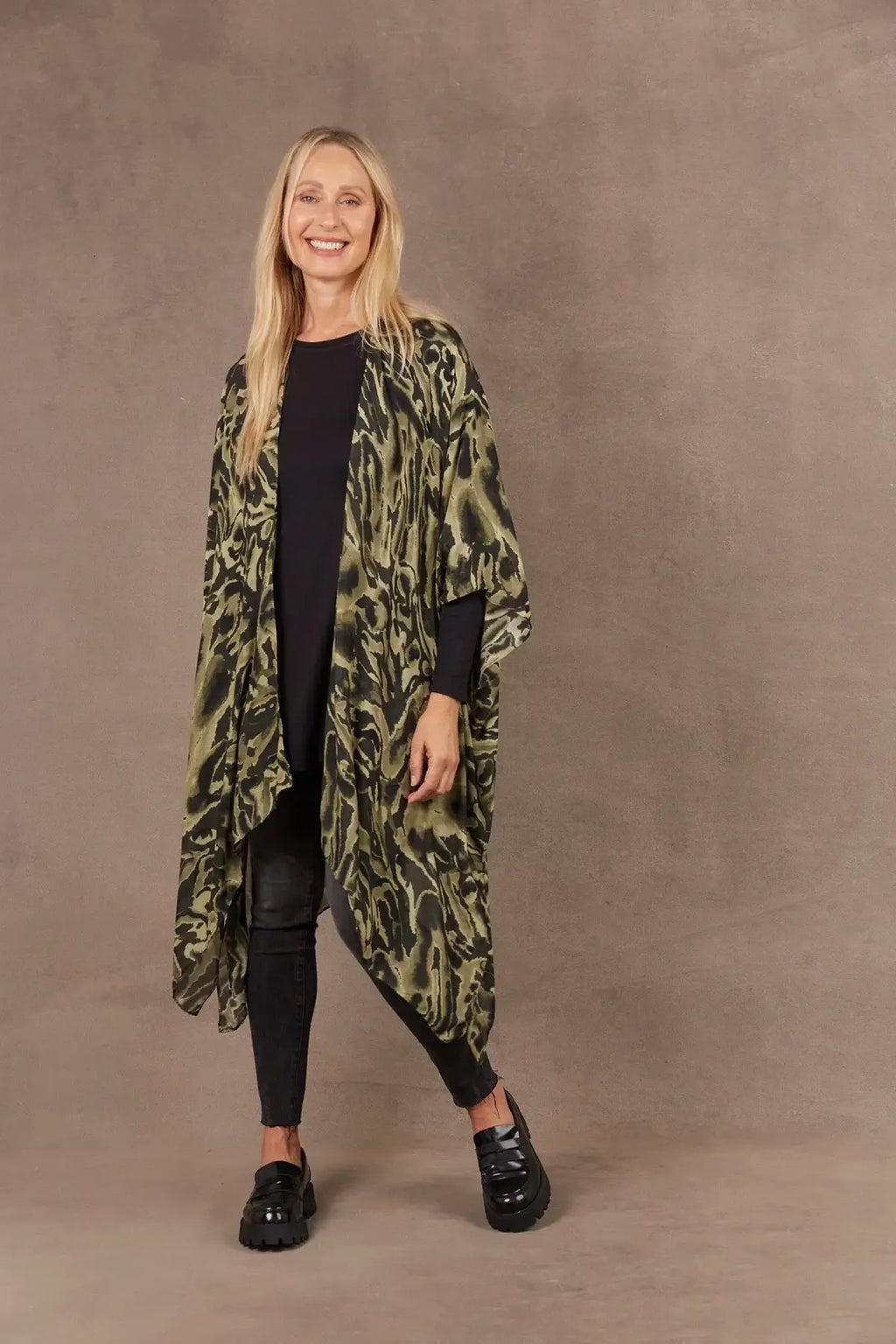 Model wearing the Mayan Cape with 3/4 length sleeves, handkerchief hem, and side vents in a stylish setting.