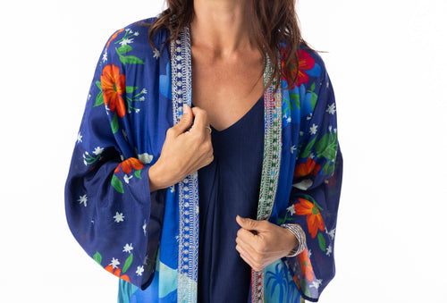 Model wears the Arabian Nights Wrap Long featuring colorful floral patterns and elegant kimono sleeves.
