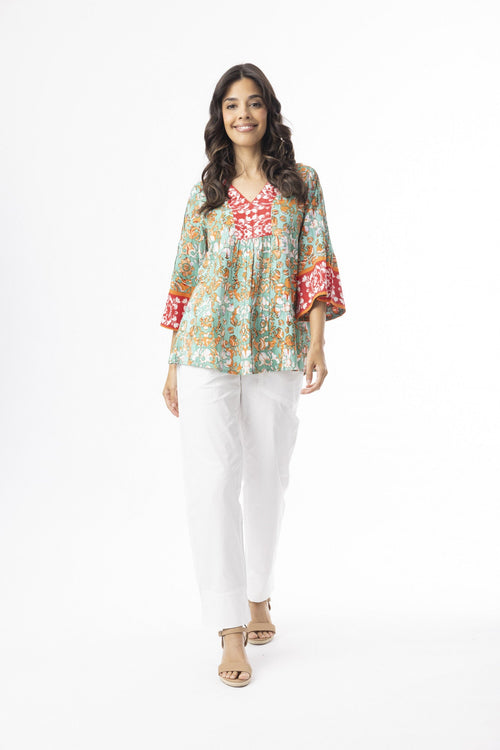 Woman wearing Araya Top V Flaired Sleeve with flared sleeves and relaxed fit, paired with white pants.