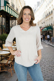 Model wearing Brishti linen/rayon top in warm beige, showcasing a V-neckline and relaxed style in a charming Parisian street.
