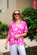 Willow Tree 32956-1-HP top in hot pink with scribble print, short sleeves, outdoor setting with foliage.