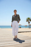 Model wearing WT Button Pant on a sunny beach boardwalk, showcasing stylish white tailoring.