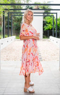 Geo Floral Panel Dress orange on model, showcasing its vibrant design and mid-calf length in a natural outdoor setting.