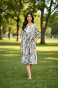 Model wearing the WT Suzy Eiffel Tower Dress Cream in a park with a relaxed silhouette and Eiffel Tower print.