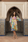 A woman wearing an Oriental Digital Tie Dress poses elegantly in a colorful, patterned dress against a stunning Moroccan backdrop.