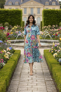 Model in a Selaron Collar patch dress walking through a vibrant flower garden, showcasing effortless elegance.