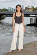 Model showcasing Tate Denim jeans Salt by Ise of Mine, featuring a mid-rise, wide-leg design by the riverside.