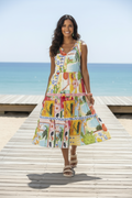 Woman in vibrant Erica Layers Sleeveless Dress walking by the beach with a wooden deck in the background.