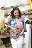 Woman wearing the Ikebana Frill Neck Top with vibrant floral patterns, perfect for a stylish everyday look.
