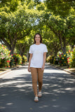 Model wearing JS Gold floral print t-shirt while strolling through a picturesque tree-lined path.