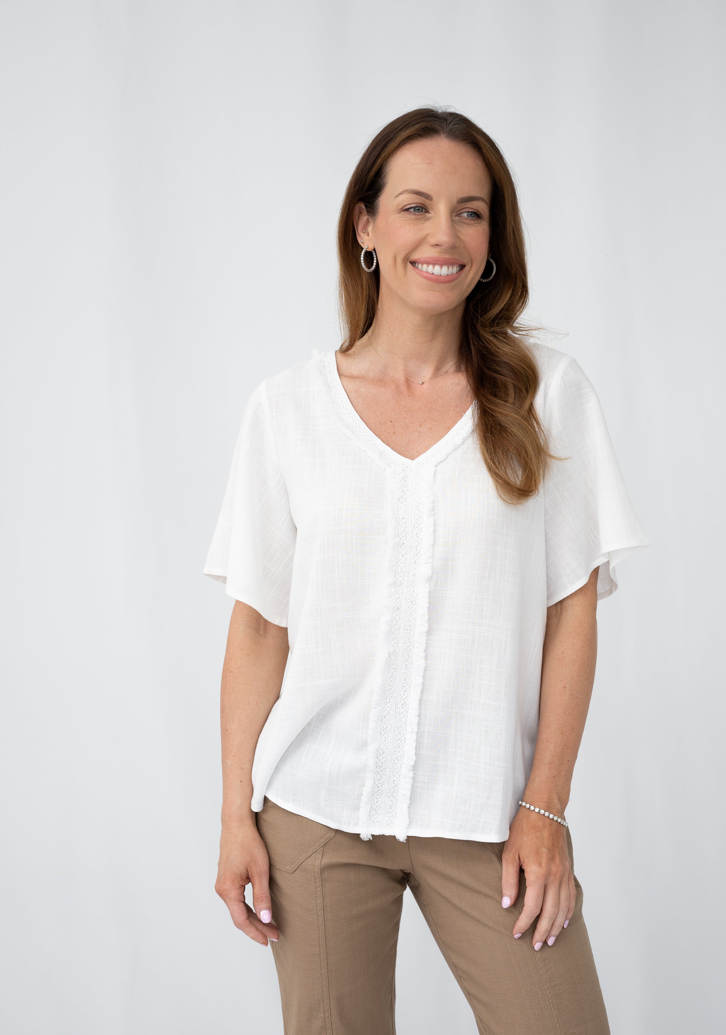 WT Lace Trim Top worn by a smiling model, showcasing a white short-sleeve top with a V-neckline and lace trim.