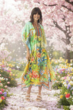 Model wearing the Georgia Kaftan surrounded by colorful flowers in a scenic garden.