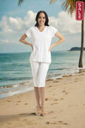 Essentials Knits V Neck T shirt model wearing white outfit on the beach with palm trees.