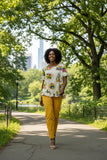 Model wearing Guatemala Frill Top in a vibrant print and yellow trousers walking in a park.
