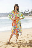 Sofia Dress Collar Buttonthrough worn by a smiling model on the beach with vibrant floral print.