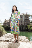 Model wearing the Sante Fe Collar Dress, showcasing vibrant colors and a waist tie, near a scenic water backdrop.