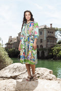 Model wearing the Sante Fe Collar Dress, showcasing vibrant colors and a waist tie, near a scenic water backdrop.