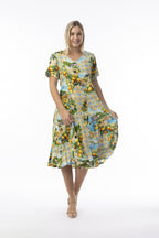 Woman wearing Amalfi Dress Godet Short Sleeve with vibrant floral print and flowing skirt, exuding summer elegance.