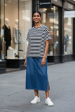 Model wearing La Paz Tshirt with stripes and a denim skirt on a city street.