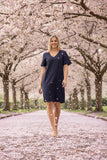 Linen Essentials Shift Dress navy worn by a model walking through a cherry blossom path, petals softly falling around.