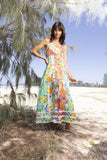 Model wearing the Sofia Maxi Strappy Dress, featuring vibrant floral patterns and a sunny beach backdrop.