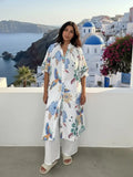 Model wearing a Parrot Shirt Dress by a scenic coastal background, showcasing the vibrant floral and parrot print.