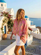 Model wearing a Botanical Lobster Shirt in a scenic Mediterranean setting with blooming flowers.