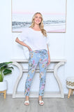 Woman wearing Floral Crinkle Pants with floral design, paired with a white top, standing in a stylish room.