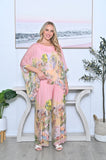 Woman wearing Silk Scenic Pants Pink with a colorful patterned top, styled in a modern interior.