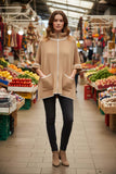 Bente Knitted Zip cape worn by a model in a colorful market, showcasing cozy sophistication and style.