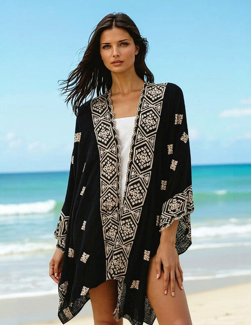 ATN Embroidered cape displayed by a model at the beach, showcasing intricate embroidery and artisan elegance.