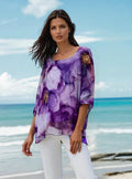 Model wearing Fia Double Layer Silky Top in purple floral design with ocean backdrop.
