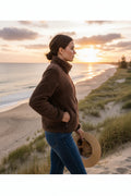 Model wearing a Teddy Jacket stands by the beach at sunset, showcasing its cozy style and plush design.