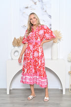 Model wearing a Pineapple Shirt Dress red, showcasing a vibrant floral design and belted waist for a stylish look.