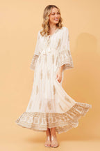 Ketia Tiered Dress featuring cream fabric with gold details, V neck, fringe, and flared sleeves.