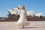 Ketia Tiered Dress worn by a woman in front of the Sydney Opera House, showcasing its elegant design and flowing skirt.