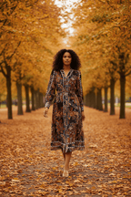 Model wearing Oriana Midi Dress walking through autumn trees with fallen leaves.