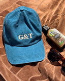 Joy Caps resting on a brown surface alongside sunglasses and a bottle, showcasing casual summer style.