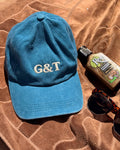 Joy Caps resting on a brown surface alongside sunglasses and a bottle, showcasing casual summer style.