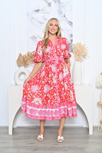 Woman wearing a Pineapple Shirt Dress red, featuring a belted waist and floral patterns against a light background.