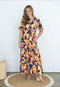 Model wearing SIS Fruitful Bloom Maxi Dress featuring colorful floral design and short sleeves.